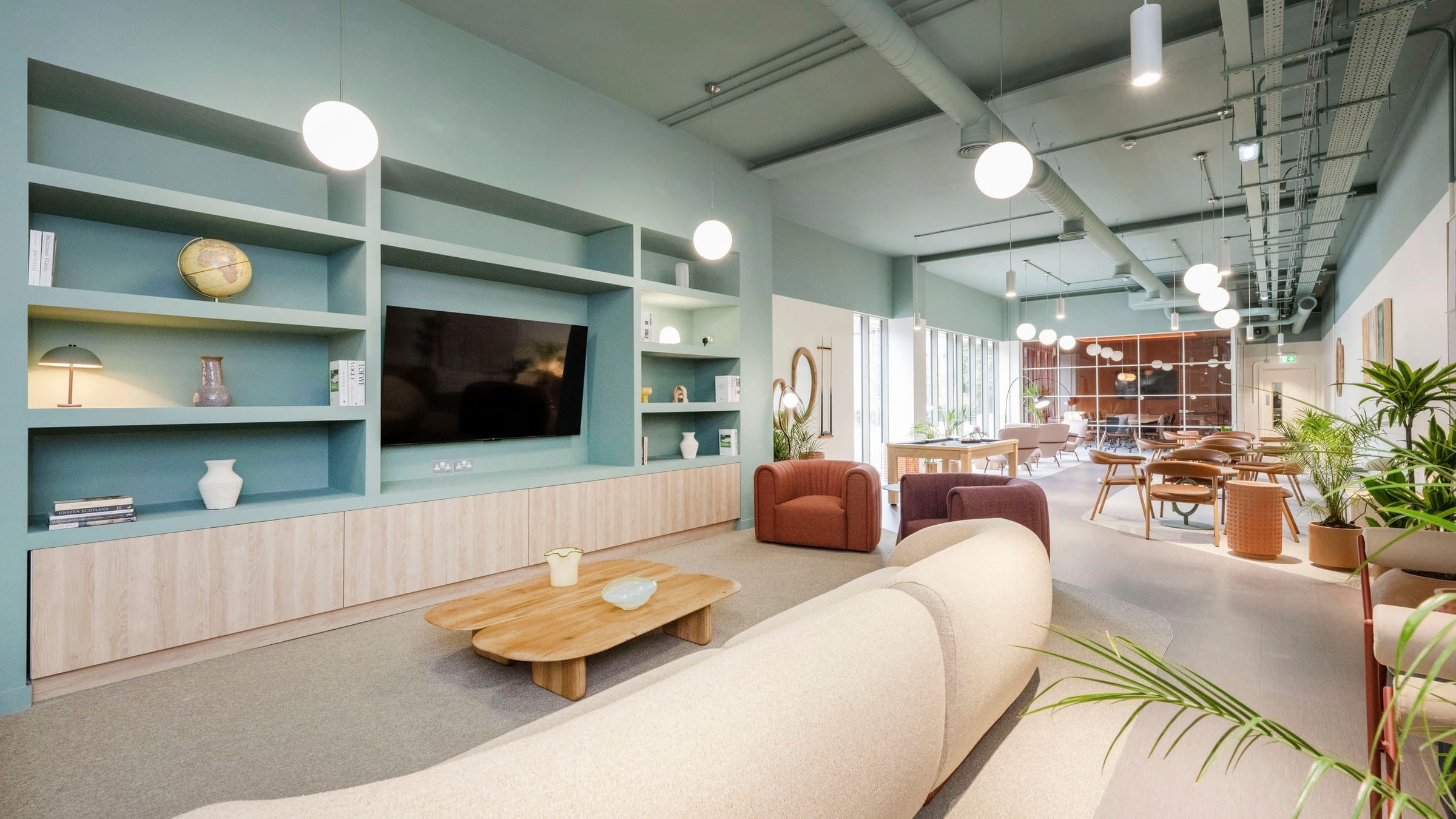 The lounge at Foundry Courtyard, with a curved sofa facing a wall-mounted television and built-in shelving